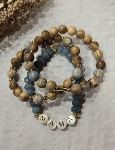 Handmade, dainty bead stack, set of 3.  Beads used- Turquoise Jasper sea sediment, natural wood, 18k gold-filled, natural stone blue beads, mother of pearl letter beads. Care: 1. Avoid contact with water, perfume and other chemicals. 2. Simply roll bracelets on and off. Do not pull or tug! 3. Take jewelry off when showering, exercising, cleaning, etc. Any fashion jewelry that is not solid gold will eventually fade over time due to moisture in the air, natural oils on your skin, etc. Sizing: Unle Mama Bracelet, Pearl Letters, Water Perfume, Letter Beads, Stretchy Bracelets, Strand Necklace, Blue Beads, Bracelet Stack, Natural Oils