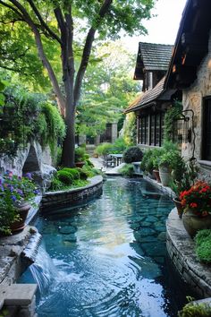 an outdoor swimming pool surrounded by greenery and flowers in front of a stone building