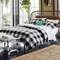 a bed with black and white checkered sheets in a room next to large windows