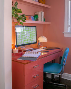 a desk with a computer on top of it and a blue chair in front of it