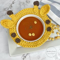 a white plate topped with a bowl of soup next to a spoon and napkin on top of a table