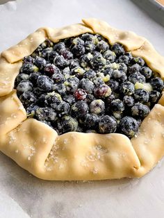 a pie crust with blueberries and powdered sugar on top, ready to go into the oven