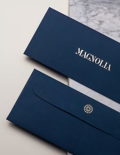 two blue envelopes sitting next to each other on top of a marble countertop