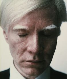 an older man with his eyes closed wearing a suit and tie in front of a white background