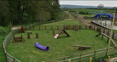 a purple tube is in the middle of a grassy area with wooden fences and playground equipment