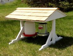 a wooden table with a bucket underneath it on the grass in front of a tree