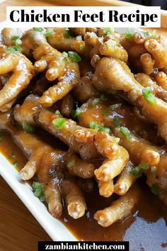 chicken feet with sauce and green onions in a white dish on a wooden table top