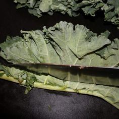 a knife is laying on top of some green leafy vegetables that have been cut in half