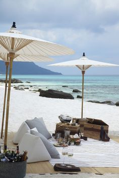 an outdoor dining area on the beach with umbrellas and drinks in front of it