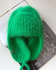 a green knitted hat sitting on top of a magazine