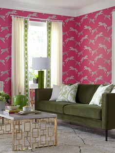 a living room with pink and green wallpaper, couches, coffee table and lamp