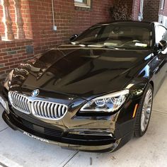 a black car parked in front of a brick building