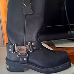 a pair of black leather boots with silver buckles on the bottom and sides, sitting on a table