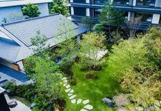 an aerial view of a garden with rocks and grass in the foreground, surrounded by two buildings