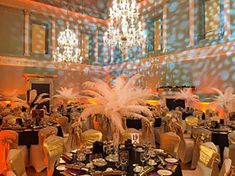 a room filled with lots of tables covered in white and gold cloths next to chandeliers