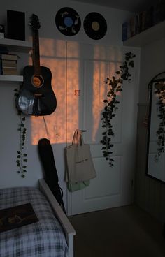 a bedroom with a guitar hanging on the wall and plants growing up against the wall