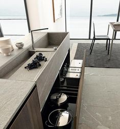 an open kitchen with pots and pans on the stove in front of large windows