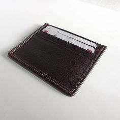 A leather cardholder is a small, compact wallet designed to hold just the essentials, typically credit cards, ID cards, and some cash. They are often made of genuine leather, providing durability and style. Leather cardholders are typically smaller in size than traditional wallets, making them a convenient option for those who prefer to carry just the essentials. They come in a range of colors, sizes, and designs, and are perfect for those who want to streamline their carry. Small and compact de Leather Rectangular Card Holder With Card Slots, Rectangular Business Coin Purse With Card Slots, Rectangular Coin Purse With Card Slots For Business, Brown Business Card Holder With Id Window, Classic Leather Coin Purse With Card Slots, Classic Brown Card Holder With Card Slots, Classic Brown Card Holder With Slots, Leather Card Holder With Id Window For Daily Use, Leather Card Holder With Slots As Gift