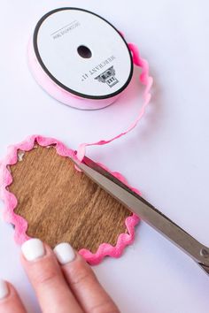 a person cutting up some pink paper with a pair of scissors on top of it