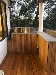 an outdoor kitchen with wood flooring and stainless steel sink on the side of it