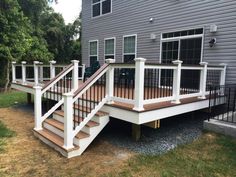 a deck with railings and stairs in front of a house