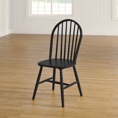 a black chair sitting on top of a hard wood floor next to a white wall