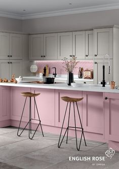 two stools in front of a pink kitchen island with white countertops and cabinets