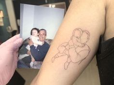 a person holding up a photo with a drawing on it's arm and the image of a baby in his arms