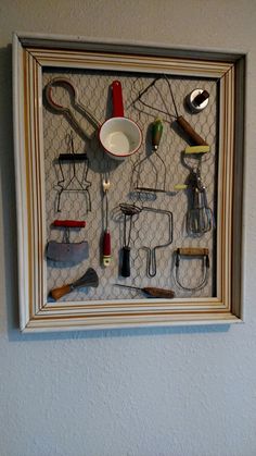 there are many kitchen utensils in the shadow box on the wall above it