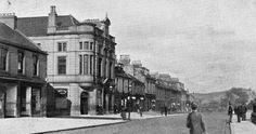 an old black and white photo of people walking down the street in front of buildings