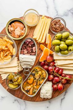 an assortment of cheeses, crackers, and fruit on a wooden platter