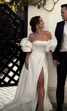 a man and woman standing next to each other in formal wear, one wearing a white dress