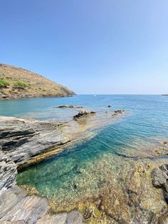 the water is crystal blue and clear at this rocky shore line, with rocks in the foreground