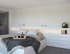 a white bed sitting in a bedroom on top of a hard wood floored floor