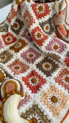 a crocheted blanket with a stuffed animal on it and a bag in the background