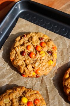 three cookies with m & ms on them sitting on top of wax paper