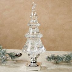 a clear glass christmas tree with pine cones