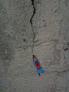 a kite that is hanging on the side of a concrete wall with cracks in it