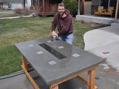 a man is sanding up a table outside in the yard with a power drill