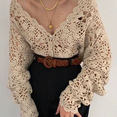 a woman wearing a crochet top and black pants with her hands in her pockets