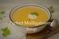 a white bowl filled with soup on top of a wooden cutting board next to a spoon