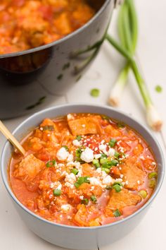 two bowls filled with food on top of a white counter next to a pot of soup