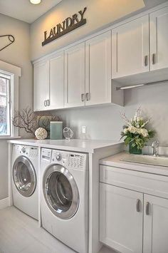 a washer and dryer in a white laundry room with cabinets on the wall