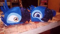 two blue birds sitting on top of a counter next to each other with eyes painted on them