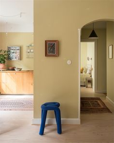 a blue stool sitting on top of a hard wood floor next to a yellow wall