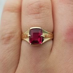 Very unique and very old, this style of ring and synthetic ruby were hot in the 1940s! This one is a 1.5 carat ruby cabochon elongated cushion cut stone in a half bezel, half prong setting. It looks great on both men and women.  - Stone is 7.8 x 6.9mm - 2.49mm band - Half bezel, half prong set - Ring is almost 100 years old - 3.61g total weight  - So retro! - Size 7.25 Classic Red Ruby Ring, Oval Cabochon, Classic Red Ruby Ring With Oval Cabochon, Classic Red Oval Cabochon Signet Ring, Classic Yellow Gold Ruby Cabochon Ring, Classic Yellow Gold Cabochon Ruby Ring, Formal Ruby Signet Ring With Bezel Setting, Vintage Red Signet Ring With Oval Cabochon, Classic 14k Gold Signet Ring With Cabochon, Ruby Signet Ring With Bezel Setting For Formal Occasions