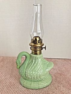 an old fashioned lamp with a green swan on it's body and a gold crown on its head