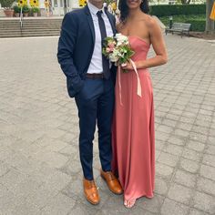 a man in a suit and tie standing next to a woman in a pink dress