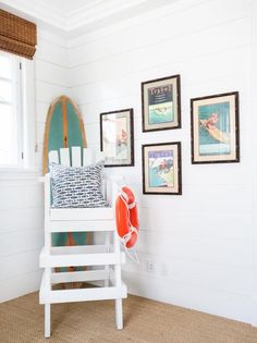 a white chair sitting next to a wall with pictures on it