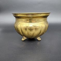 a gold colored vase sitting on top of a table next to a gray wall and floor